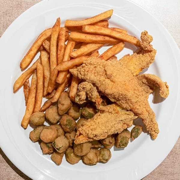 A white plate holds fried fish fillets, golden french fries, and crispy fried okra.