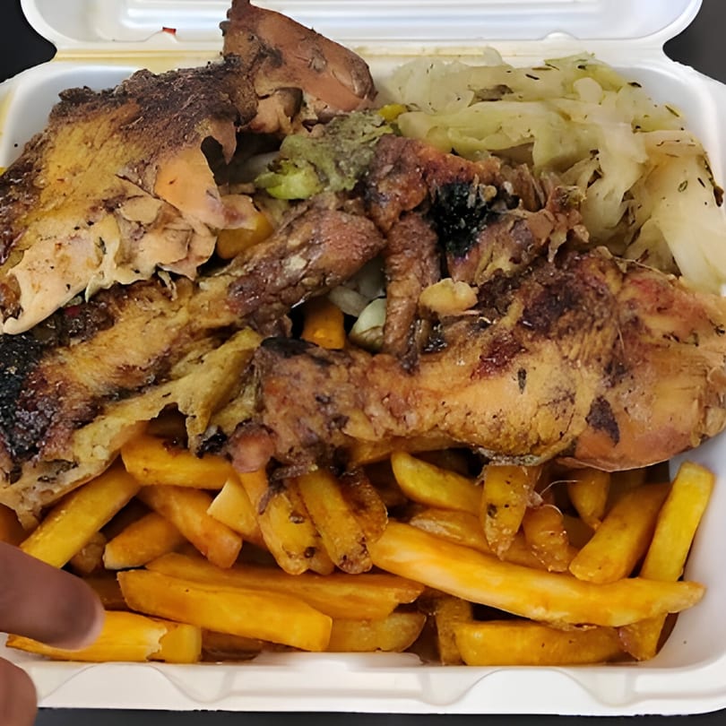 Jamaican jerk chicken with fries and cabbage in a white takeout container.