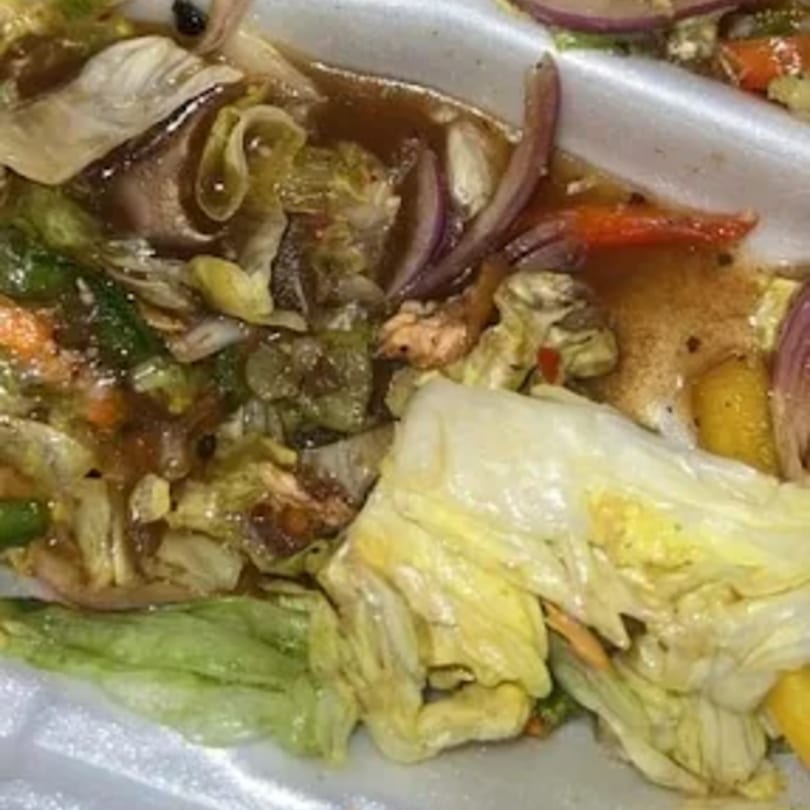 Close-up of a vibrant Jamaican salad with lettuce, red onions, and other vegetables in a dressing.